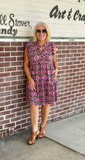 Moss green and pink tiered dress with flutter sleeves and pockets, styled with brown heeled sandals.
