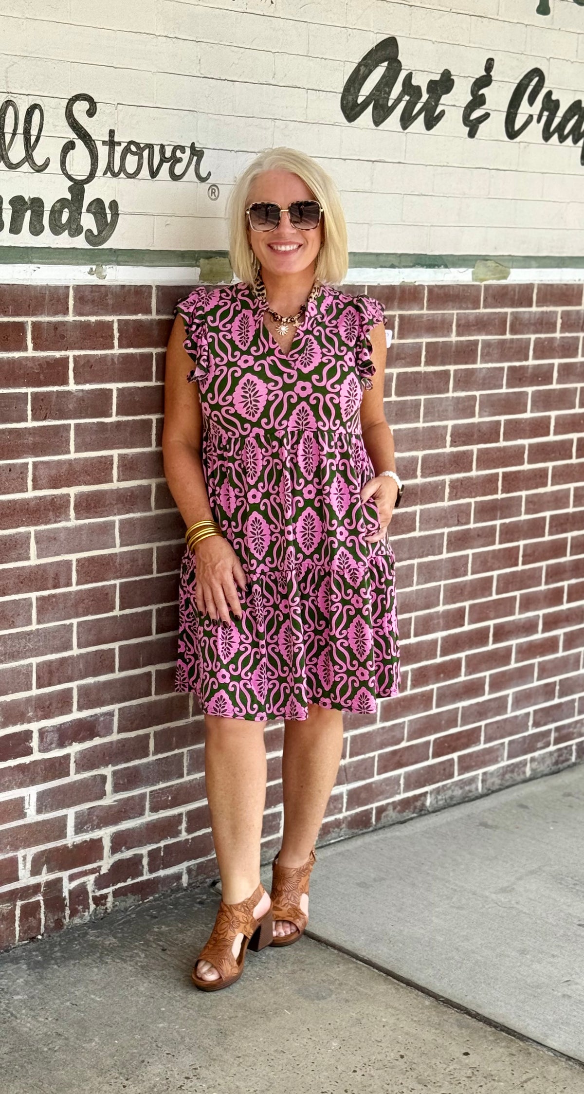 Moss green and pink tiered dress with flutter sleeves and pockets, styled with brown heeled sandals.