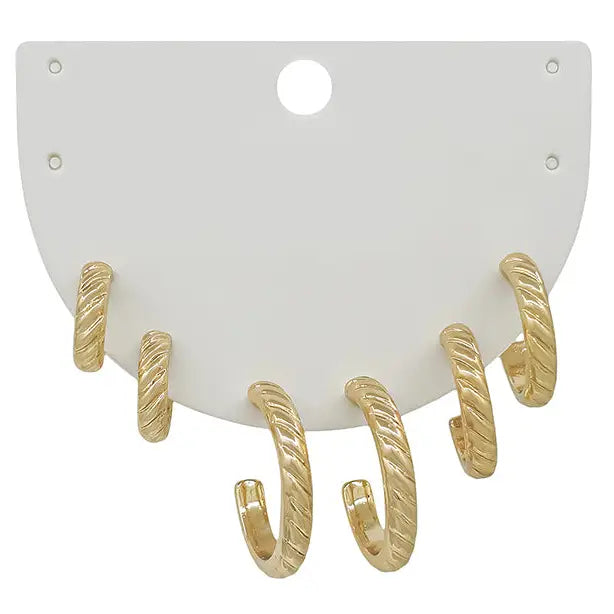 Set of three gold huggie-style earrings with a twisted design displayed on a white card.