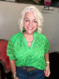 Vibrant green lace top with floral pattern, split V-neck, and short puff sleeves styled with denim.