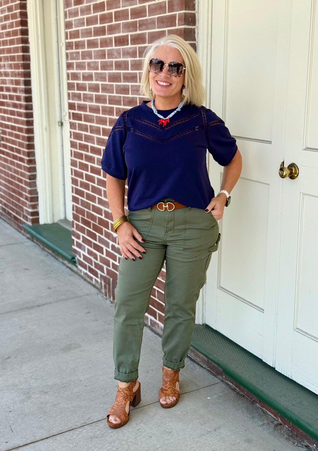 Olive green jogger with elastic waist and tapered legs, styled with a navy top and brown accessories outdoors.