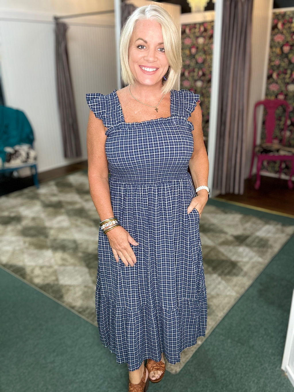 Navy sleeveless midi dress with ruffle straps, check pattern, and smocked bodice, featuring convenient pockets.