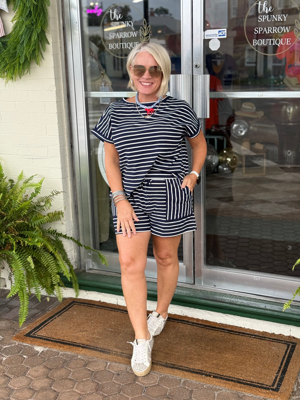 Model wearing a navy and white striped short sleeve top and matching shorts, showcasing a relaxed fit outside a boutique.