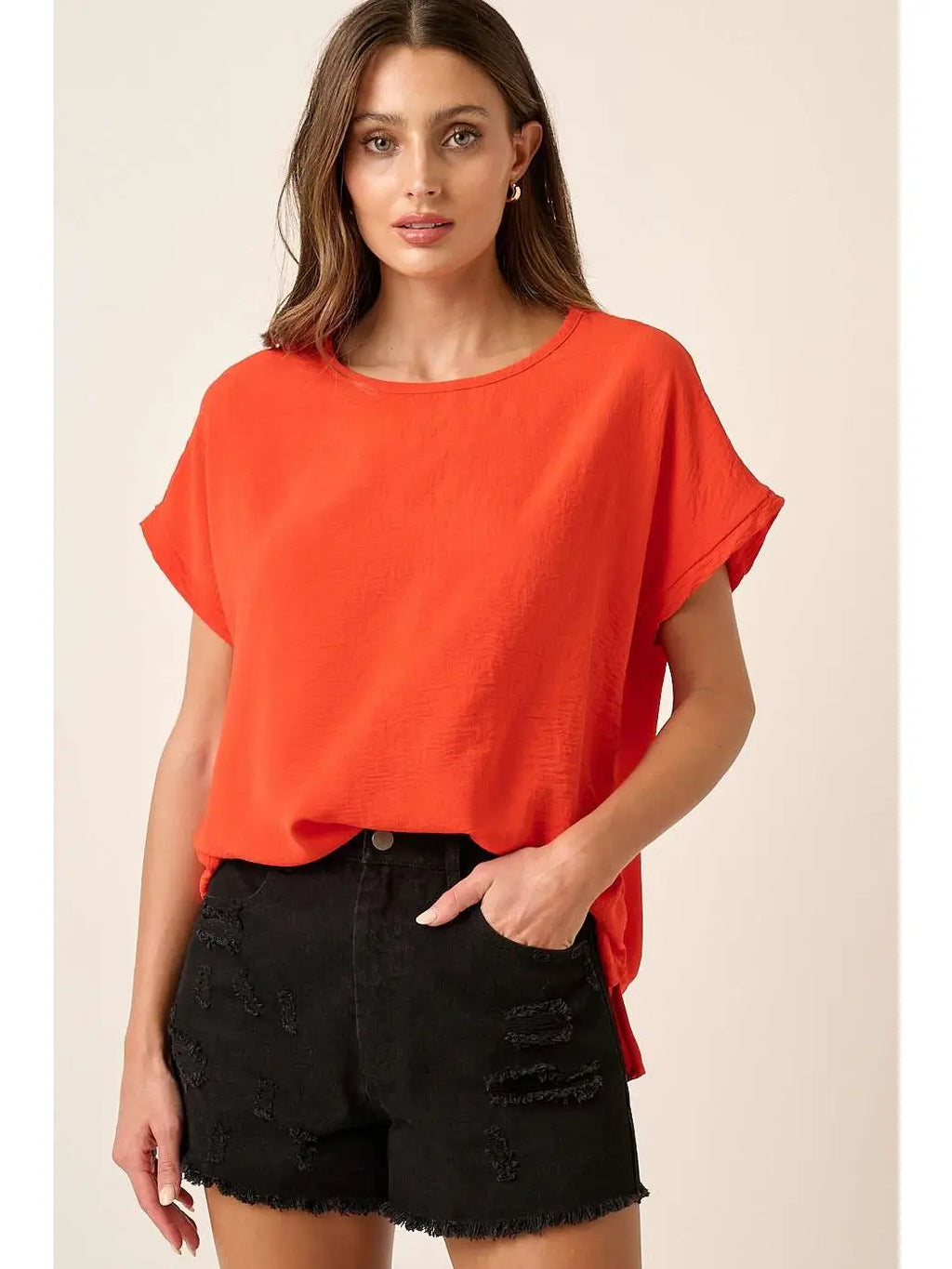 Vibrant orange oversized top with short dolman sleeves and a round neckline, styled with black shorts.