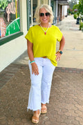 Bright lime top with relaxed fit and short dolman sleeves, styled with white pants and accessories outdoors.