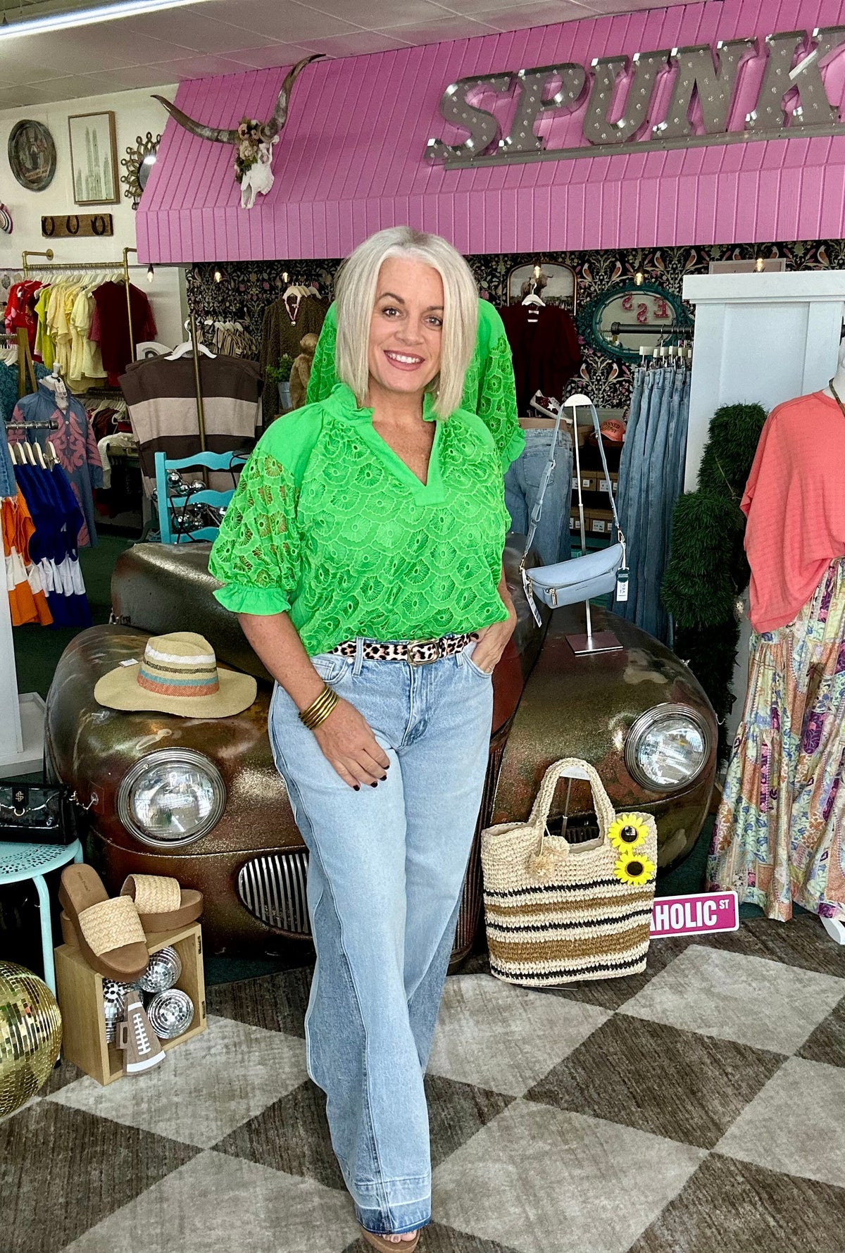 Light wash wide leg jeans styled with a casual top near a vintage car and colorful clothing displays.