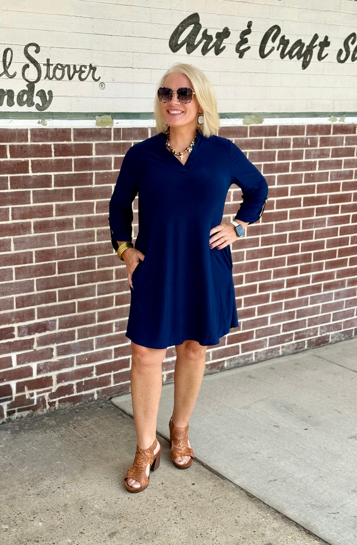 Navy A-line dress with ruffle neckline and 3/4 sleeves, styled with brown heeled sandals and accessories.