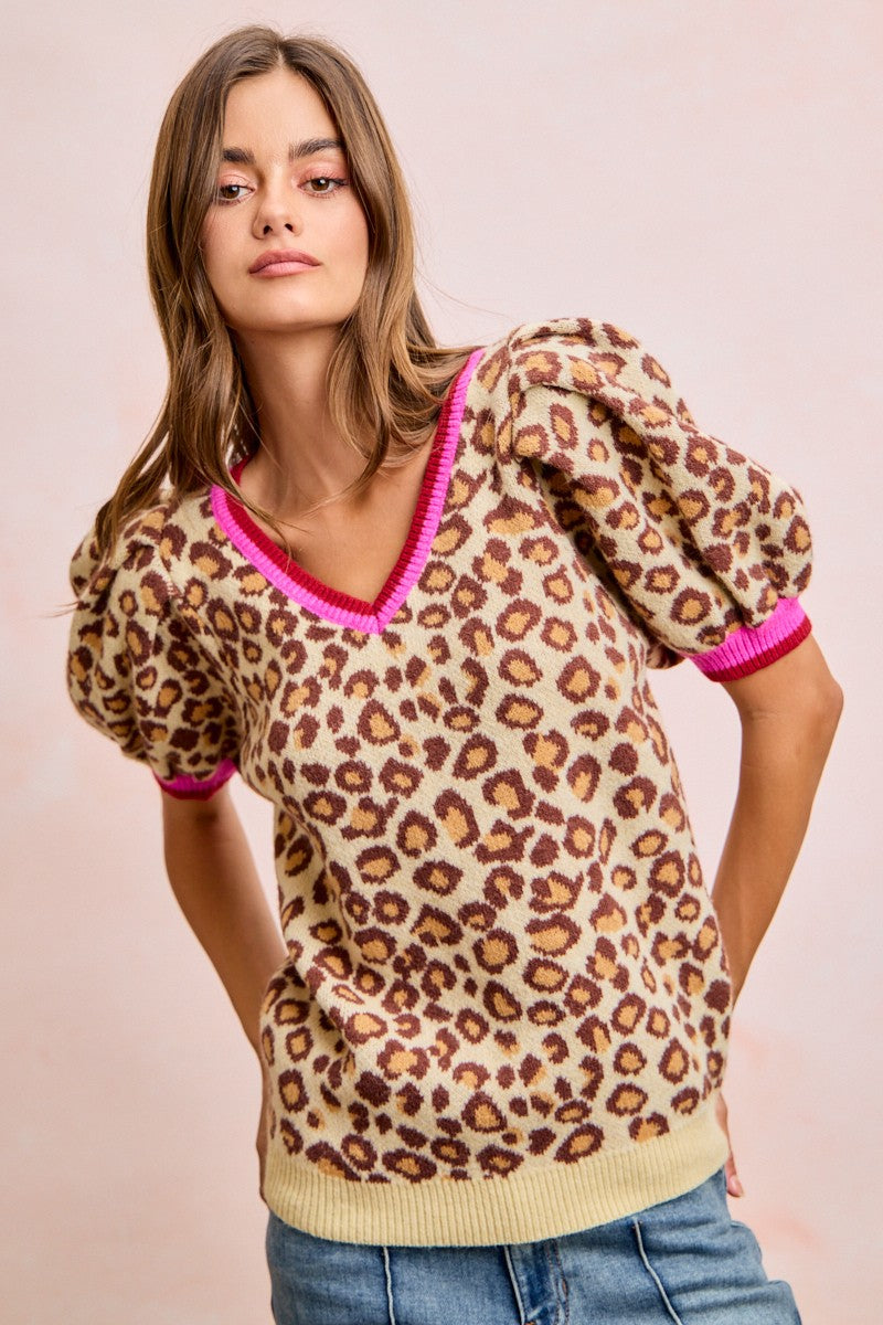 Leopard pattern puff sleeve v-neck sweater top with contrasting pink trim, styled casually.