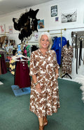 Brown floral print midi dress with 3/4 sleeves and waist tie, styled with brown ankle boots.