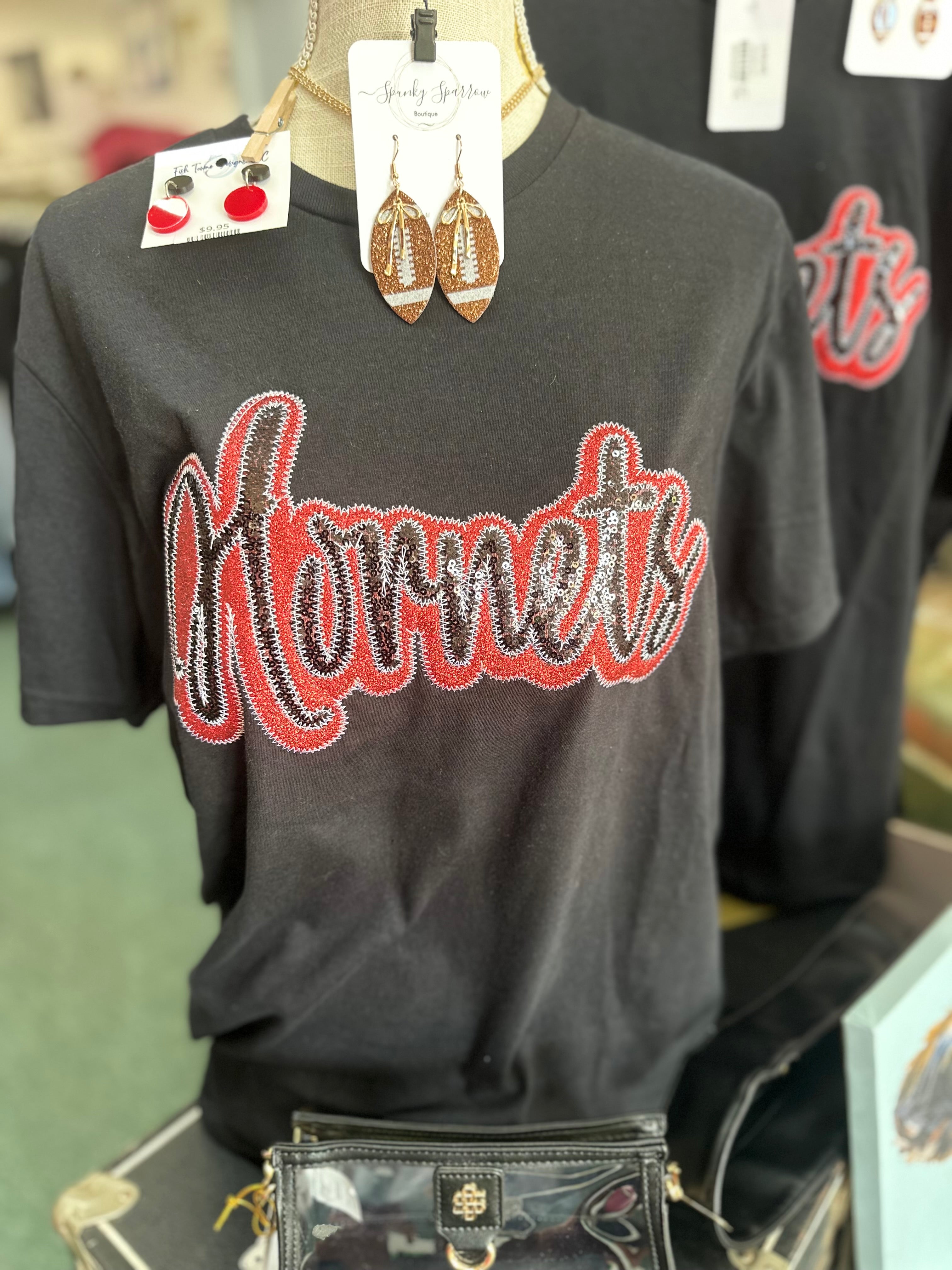 Black short sleeve T-shirt with sequined 'Hornets' design in red and silver, displayed on a mannequin with accessories.
