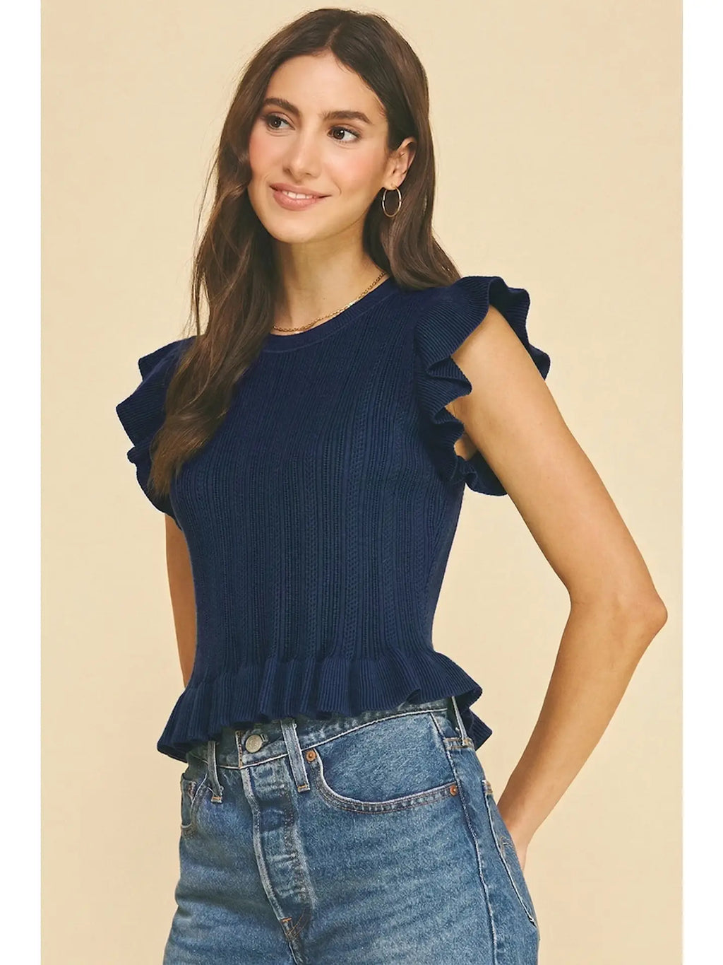 Navy ribbed knit top with ruffled sleeves and hem, styled with high-waisted denim jeans.