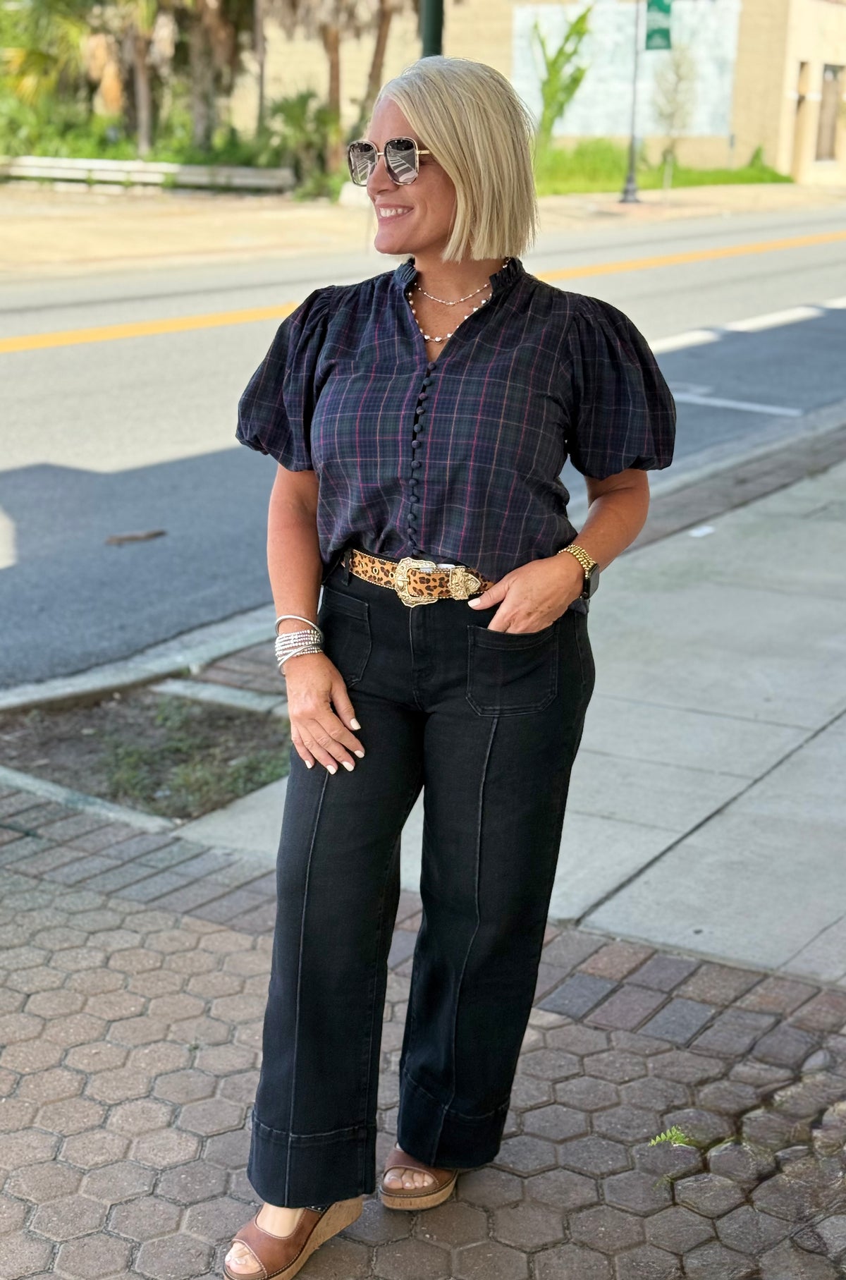 Navy plaid blouse with puff sleeves and V-neck, styled with high-waisted black pants and sunglasses outdoors.