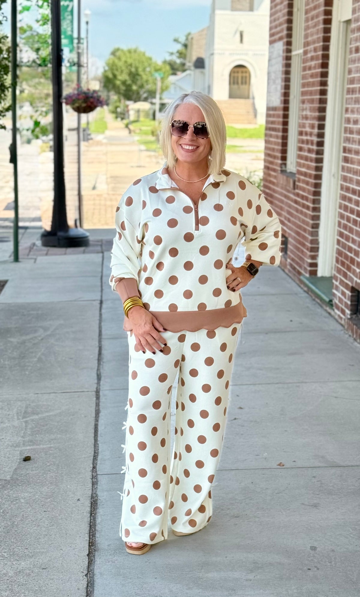 Cream polka dot outfit set featuring a three-quarter zip top and drawstring pants with scallop detailing.