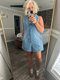 Sleeveless denim romper with V-neckline, oversized collar, full button front, and side pockets.