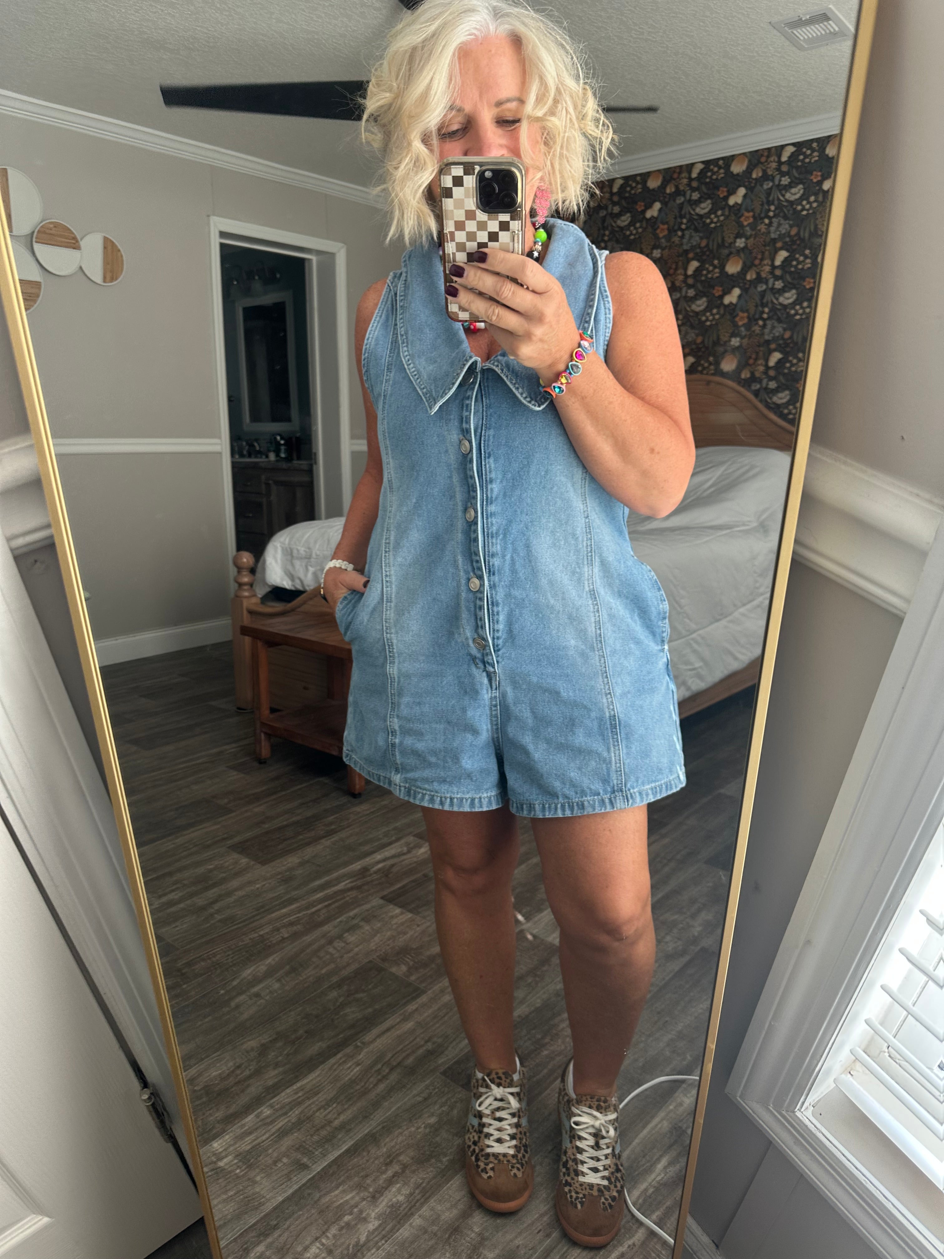Sleeveless denim romper with V-neckline, oversized collar, full button front, and side pockets.