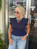 Navy ribbed knit top with ruffled sleeves and hem, styled with high-waisted jeans and accessories.