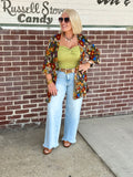 Person wearing a flowy open front cardigan with smocked sleeves and a colorful floral pattern, paired with light blue wide-leg jeans.