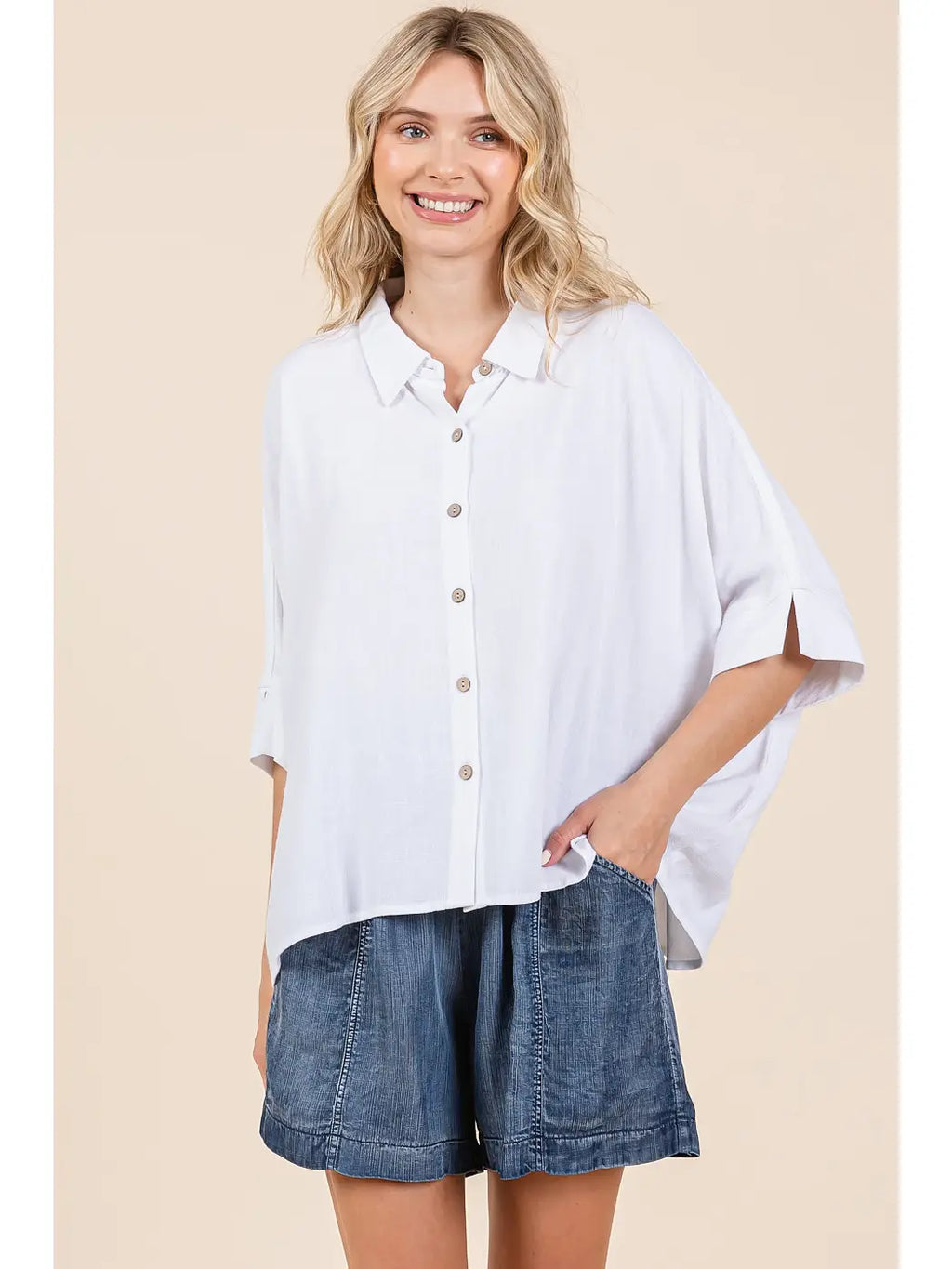 Ivory oversized button down shirt with a classic collar, buttoned placket, and cuffed short sleeves, styled with denim shorts.