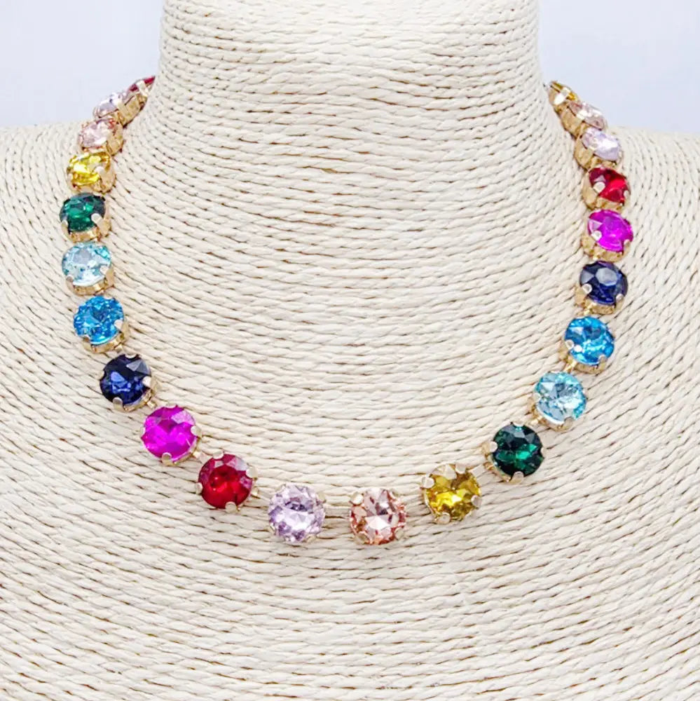 Vibrant multi-color crystal necklace displayed on a textured surface, showcasing its adjustable design and circular arrangement.