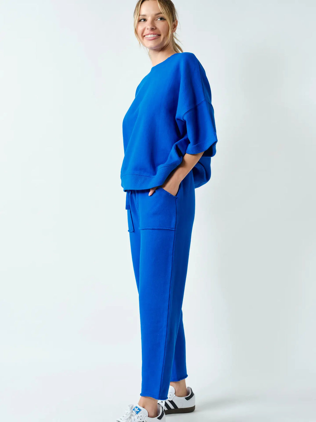 Model wearing a blue two-piece lounge set with an oversized drop shoulder top and relaxed-fit pants featuring side pockets.