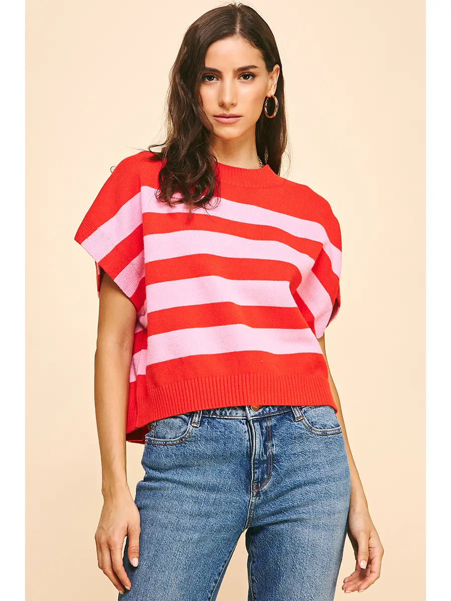 Bold red and pink striped sweater vest with a crew neck design, styled over high-waisted jeans.