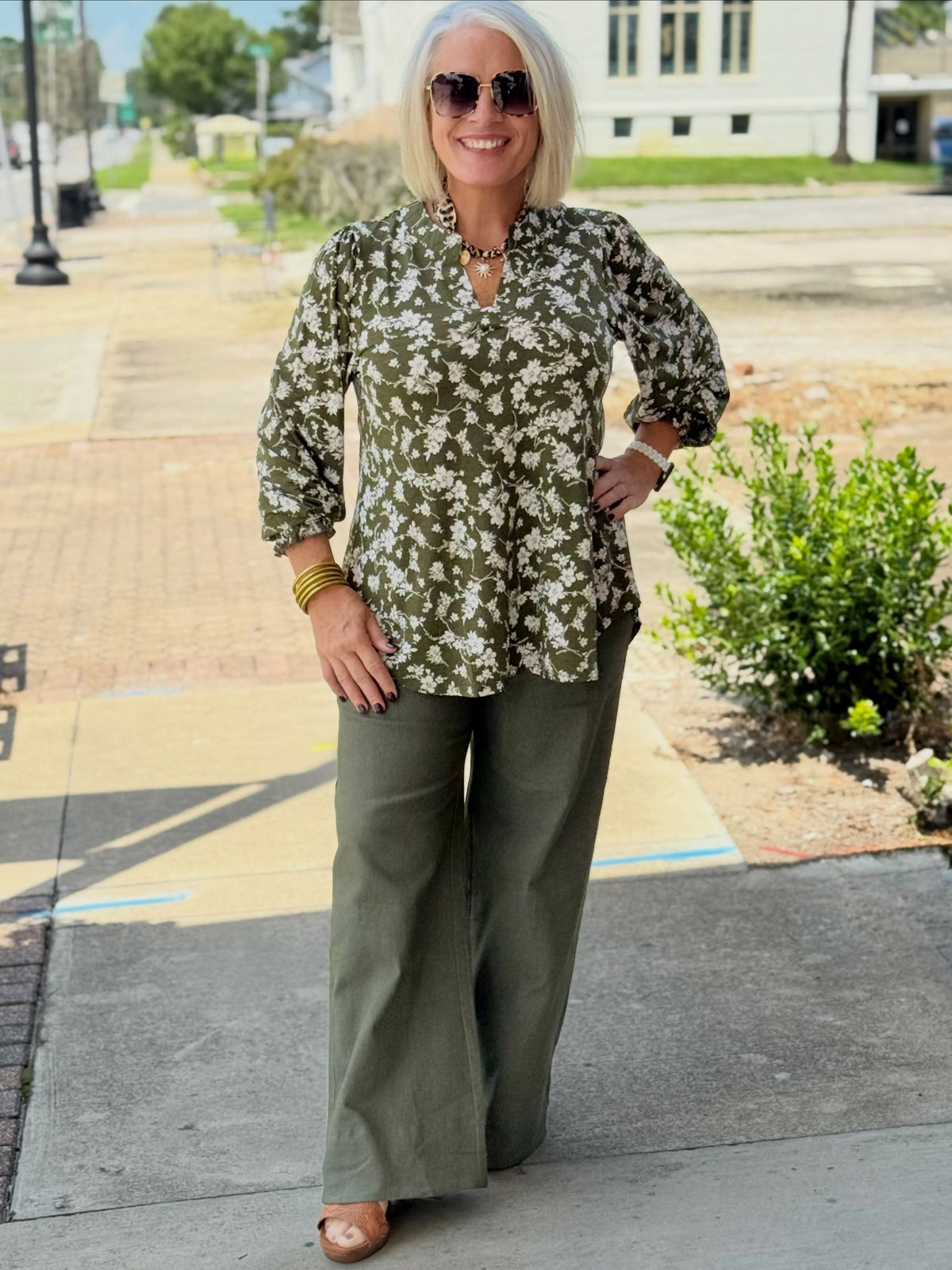 Person wearing olive high-rise wide-leg pants with front pockets, styled with a floral top and accessories.
