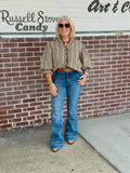 Brown check print button-down shirt with three-quarter gathered balloon sleeves styled with a belt and flared jeans against a brick wall.